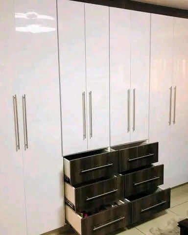 Built-in bedroom wardrobe in white gloss with dark wood drawers