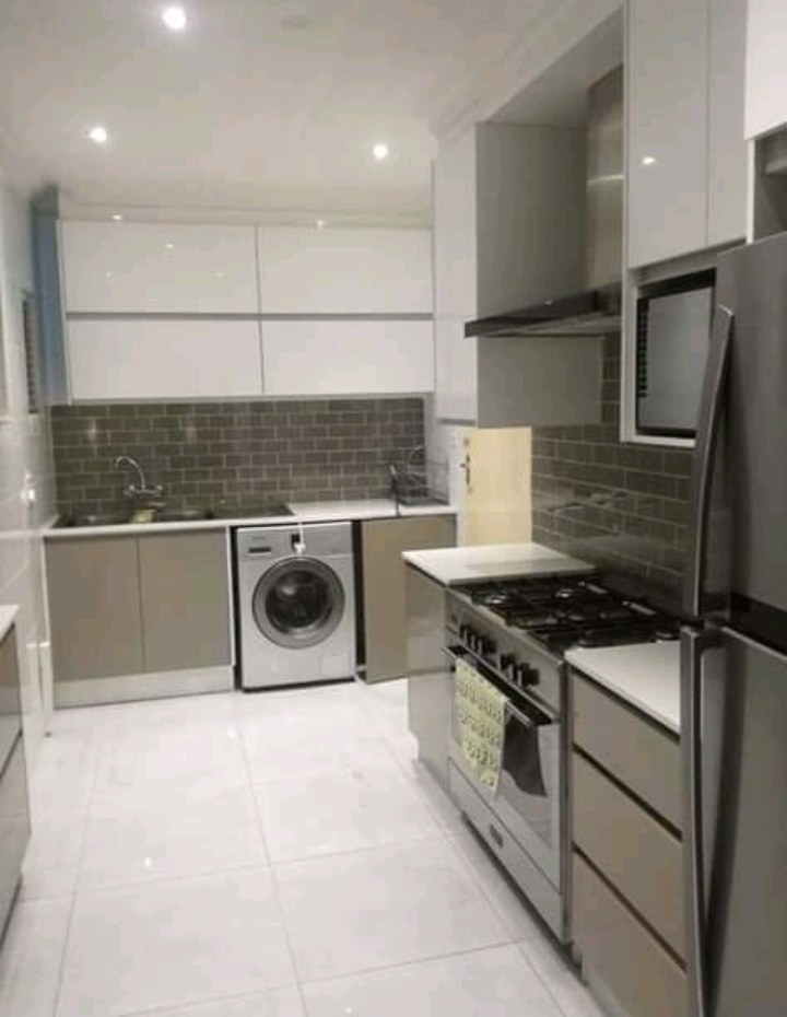Compact kitchen with white upper cabinetry and tiled backsplash