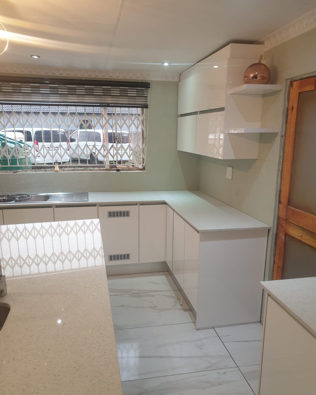 White L-shaped kitchen with stone countertops and granite-look flooring