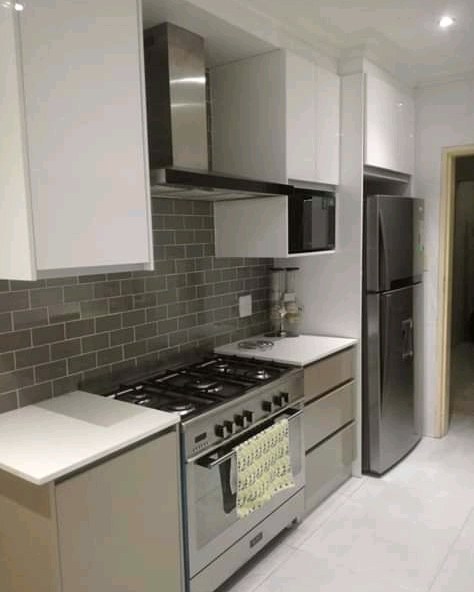 Galley kitchen with white cabinetry, gas hob and grey subway tile splashback