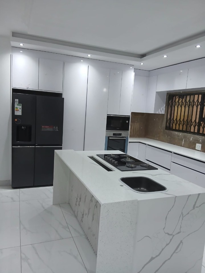 Contemporary white kitchen with marble island and dark appliances