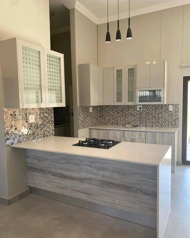 Kitchen island with gas hob, mosaic splashback and pendant lighting