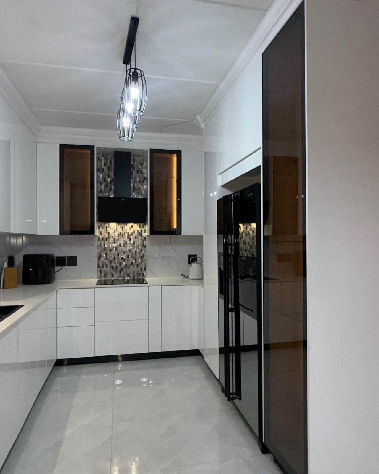 White kitchen with mosaic splashback, corner sink and pendant lighting