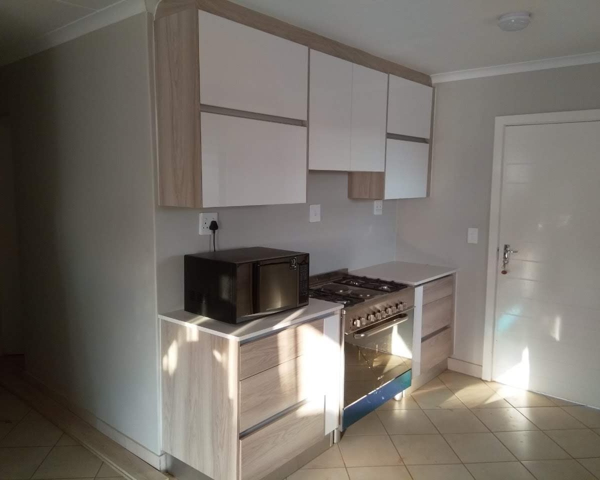 Kitchen with light oak cabinetry, white counters and freestanding gas stove